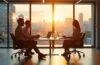 In einem hell erleuchteten, modernen Büro mit großen Fenstern sitzen internationale Fachkräfte entspannt im Gespräch, während lebendige Sonnenstrahlen durch das Glas fallen und eine warme, einladende Atmosphäre schaffen, die Effizienz, Zusammenarbeit und technologische Innovation symbolisiert.