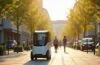 In einem sonnendurchfluteten urbanen Quartier gleitet ein moderner, schlanker autonomer Lieferroboter leise und selbstständig über den Gehweg, umgeben von freundlichen Passanten und grünen Stadtbäumen, die eine warme Atmosphäre innovativer Nachhaltigkeit und zukunftsweisender Mobilität ausstrahlen.