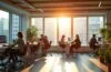 Ein lichtdurchflutetes, modernes Büro mit konzentrierten Entwickler:innen, die in warmer Atmosphäre gemeinsam an hochmodernen Datenvisualisierungen und digitalen Dashboards arbeiten, umgeben von natürlichen Holzelementen und großen Fenstern, die weiches Tageslicht hereinlassen und Innovation sowie kollaborative Zukunftsgestaltung ausstrahlen.