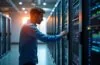 In einem lichtdurchfluteten, modernen Rechenzentrum montiert ein IT-Spezialist mit konzentriertem Lächeln modulare Serverkomponenten in einem eleganten Rack, umgeben von warmem Tageslicht und klaren, realistischen Details, die Flexibilität und zukunftsweisende Technologie greifbar machen.