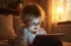 Ein warm ausgeleuchtetes, natürliches Porträt eines nachdenklichen Kindes, das mit einem Tablet in einem gemütlichen, lichtdurchfluteten Wohnraum spielt, umgeben von sanften Farben und einer Atmosphäre vertrauensvoller Nähe und behutsamer digitaler Entdeckung.