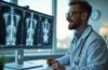 In einem hell erleuchteten modernen Krankenhauslabor analysiert ein freundlicher, konzentrierter Radiologe mit warmem Lächeln geduldig digitale MRT-Bilder auf einem Bildschirm, während sanftes Tageslicht durch große Fenster fällt und eine Atmosphäre von Hoffnung und Fortschritt in der Krebsdiagnostik vermittelt.