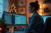 In einem lichtdurchfluteten Büro mit weihnachtlicher Dekoration sitzt eine konzentrierte Mitarbeiterin vor mehreren Bildschirmen, die E-Mails mit Warnhinweisen anzeigen, während warmes Tageslicht ihre entschlossene Miene sanft umspielt und eine beruhigende Atmosphäre von Wachsamkeit und Schutz ausstrahlt.