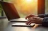 Ein hell erleuchteter, moderner Arbeitsplatz mit einem aufgeschraubten Laptop und einer handlichen SSD-Festplatte in warmer Nachmittagssonne, während die Hände einer Person sorgsam die Technik inspizieren und so Bild und Vertrauen in Datensicherheit und verantwortungsbewusste Pflege vermitteln.