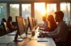 Ein lichtdurchflutetes, modern gestaltetes Büro mit konzentriert arbeitenden Menschen an vernetzten Computern und großen Fenstern, die warmes Tageslicht hereinlassen und die zentrale Bedeutung einer stabilen Internetverbindung für digitale Arbeitsprozesse lebendig und einladend vermitteln.