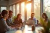 Ein strahlendes Büro mit sonnendurchfluteten Fenstern, in dem ein lächelndes, diverses Team von Recruitern und Bewerbern entspannt an modernen Laptops und Tablets arbeitet, während warmes Tageslicht die fokussierte, zukunftsorientierte Atmosphäre des KI-gestützten Recruitingprozesses lebendig und einladend einfängt.