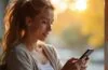 Ein strahlendes, authentisches Porträt einer entspannten Person in hellem Tageslicht, die mit einem Smartphone in der Hand aufmerksam und gelassen ihre digitalen Sicherheitseinstellungen überprüft, umgeben von einem modernen, wohnlichen Umfeld voller natürlicher Farben und warmer Stimmung.